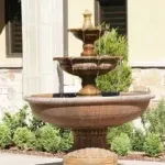 A three-tiered fountain elegantly positioned in front of a building, enhancing the landscape's beauty.