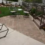A patio featuring a table and chairs, situated in front of a house, showcasing a serene outdoor setting.